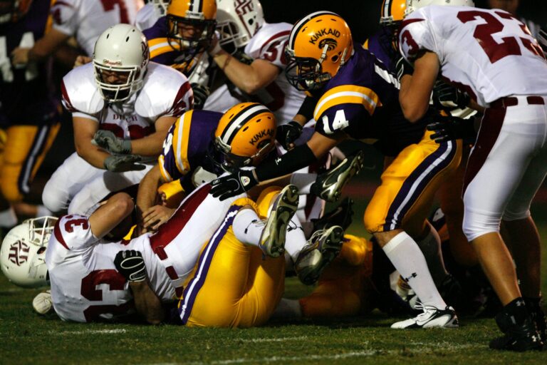 American football players piled up in a tackle during a night game