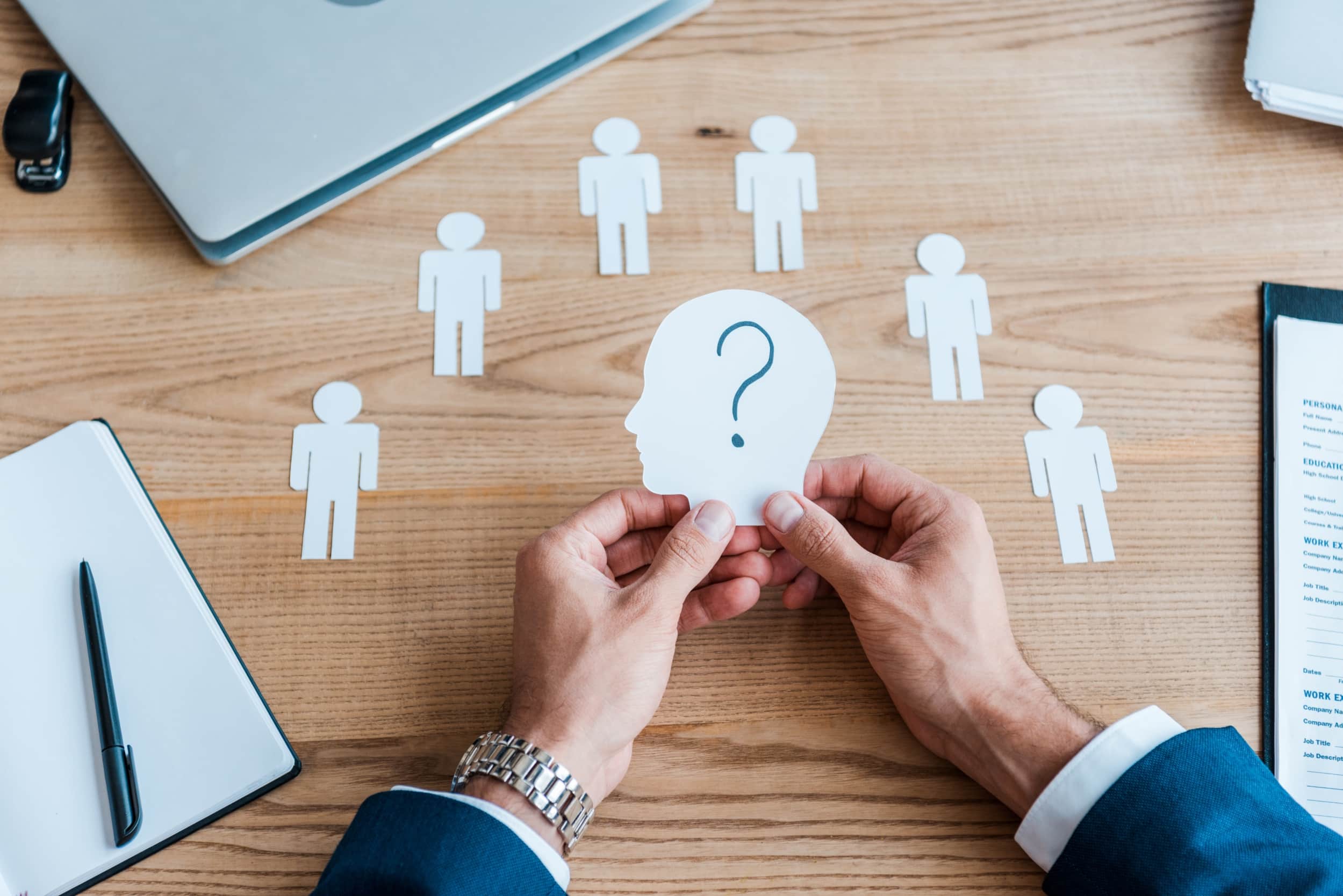 cropped view of recruiter holding paper human shape with question mark on table